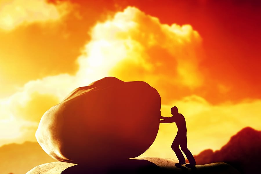 Man pushing a giant, heavy stone, rock over the mountain. Concep